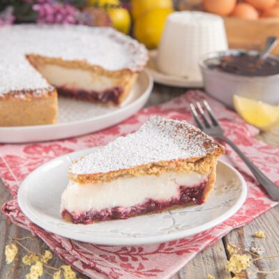Fetta di crostata ricotta e visciole con confettura e spolverata di zucchero a velo