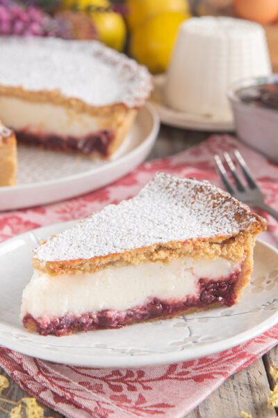 Fetta di crostata ricotta e visciole con confettura e spolverata di zucchero a velo