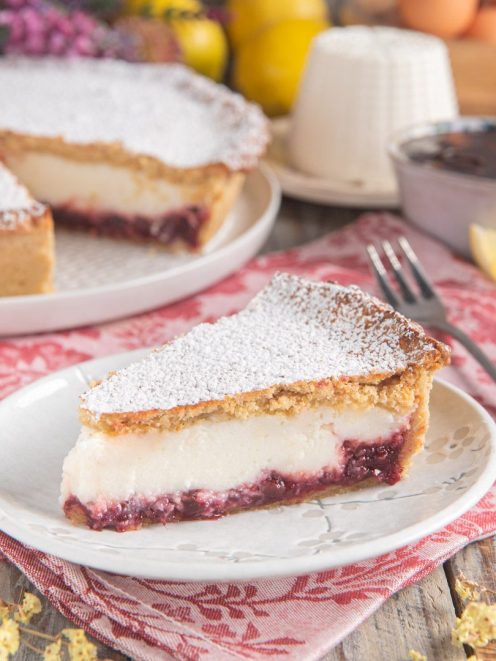 Fetta di crostata ricotta e visciole con confettura e spolverata di zucchero a velo