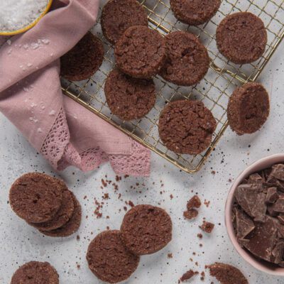 Diamantini al cioccolato disposti su una gratella e sul piano, con scaglie di cioccolato fondente accanto