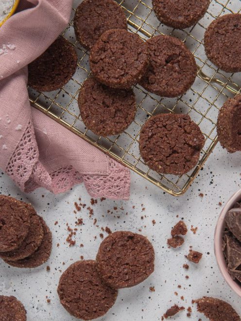 Diamantini al cioccolato disposti su una gratella e sul piano, con scaglie di cioccolato fondente accanto
