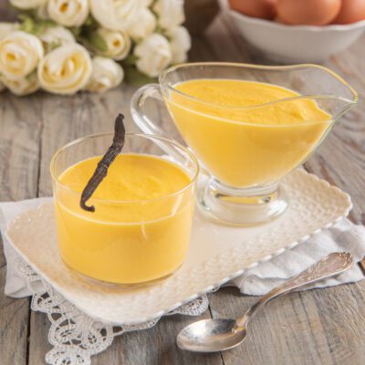 Salsa alla vaniglia servita in una coppetta e in una salsiera, guarnita con un baccello di vaniglia