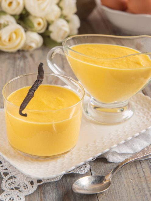 Salsa alla vaniglia servita in una coppetta e in una salsiera, guarnita con un baccello di vaniglia