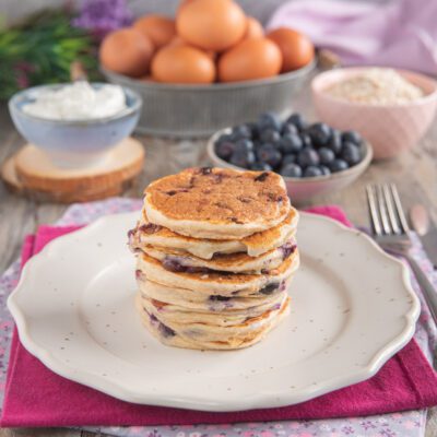 Pancakes allo yogurt e mirtilli impilati con i frutti visibili tra uno strato e l'altro