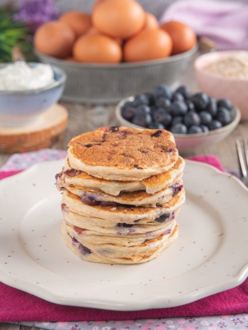 Pancakes allo yogurt e mirtilli impilati con i frutti visibili tra uno strato e l'altro