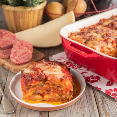 Parmigiana di patate e melanzane con cotechino a strati, con sugo di pomodoro e mozzarella filante