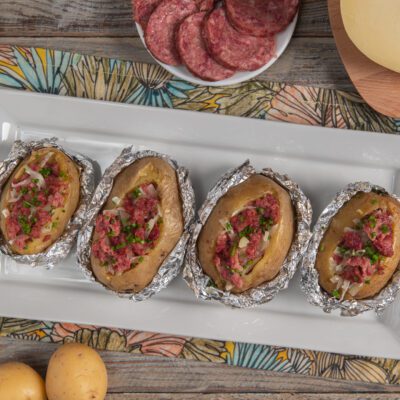 Patate al forno ripiene di cotechino sbriciolato, cipolla e erba cipollina, avvolte in carta stagnola