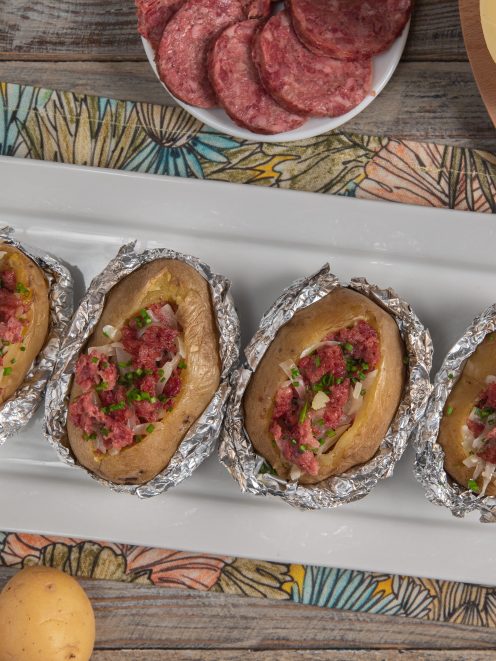 Patate al forno ripiene di cotechino sbriciolato, cipolla e erba cipollina, avvolte in carta stagnola