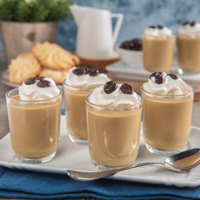 Cremoso al caffè servito in bicchieri con panna montata e chicchi di caffè