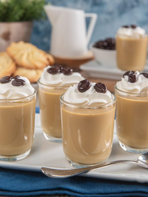 Cremoso al caffè servito in bicchieri con panna montata e chicchi di caffè