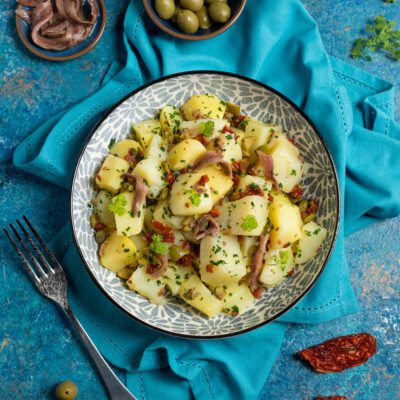 Insalata di patate con acciughe, olive, pomodori secchi, capperi e prezzemolo fresco