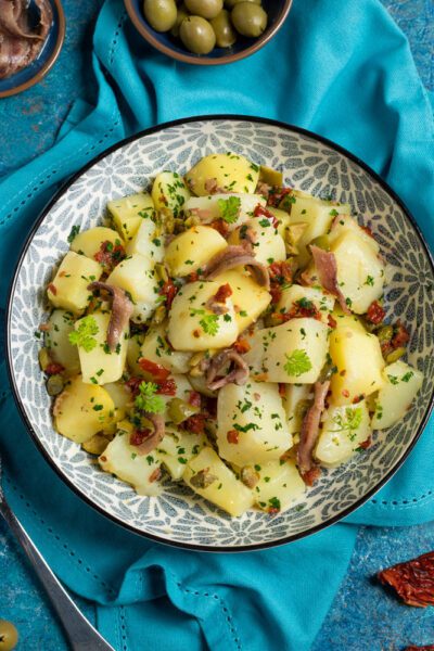 Insalata di patate con acciughe, olive, pomodori secchi, capperi e prezzemolo fresco