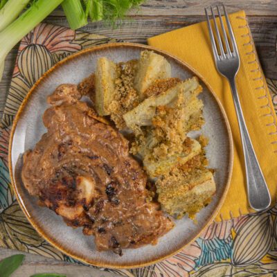 Ossibuchi di vitello alla senape antica con salsa ricca, serviti accanto a finocchi al forno gratinati