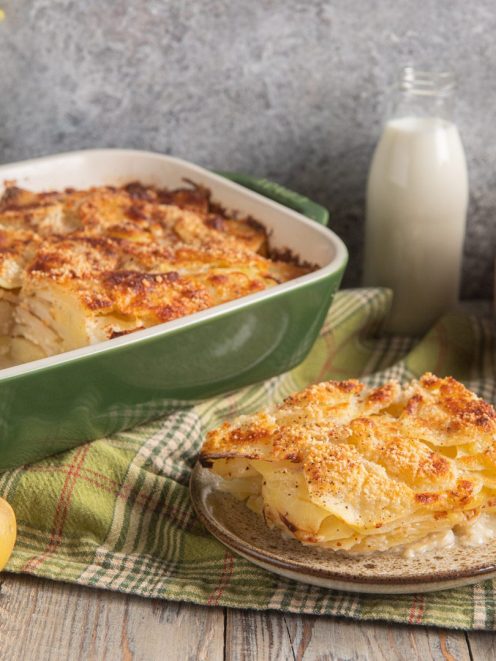 Patate alla romana gratinate con crosta dorata, servite a fette con strati di patate a fette