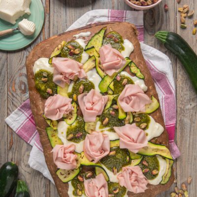 Focaccia ai cereali farcita con stracchino, zucchine grigliate, pesto di pistacchi e rose di mortadella