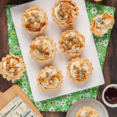 Tartellette al gorgonzola con gocce di miele e granella di noci su vassoio