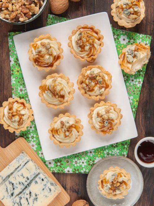 Tartellette al gorgonzola con gocce di miele e granella di noci su vassoio
