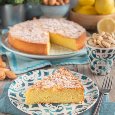 Torta di mandorle molisana con una fetta tagliata che mostra l'interno morbido, mandorle a lamelle e zucchero a velo in superficie
