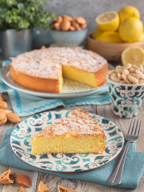 Torta di mandorle molisana con una fetta tagliata che mostra l'interno morbido, mandorle a lamelle e zucchero a velo in superficie