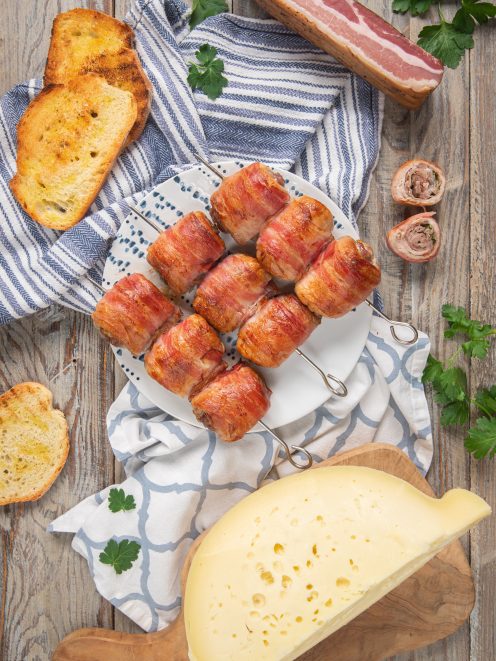 Bombette pugliesi avvolte nella pancetta e infilzate su spiedini, servite con formaggio e pane tostato