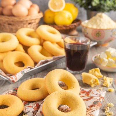 Ciambelline d'Aosta appena sfornate impilate accanto a limoni, uova e un bicchiere di vino rosso