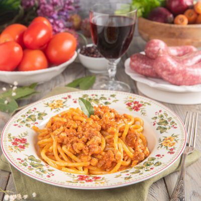 Pici al ragù di cinta senese conditi con sugo di pomodoro e carne sfilacciata, guarniti con una foglia di salvia