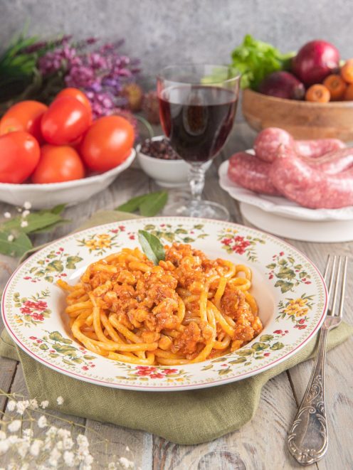 Pici al ragù di cinta senese conditi con sugo di pomodoro e carne sfilacciata, guarniti con una foglia di salvia