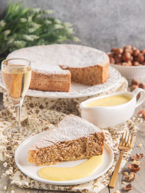 Torta di nocciole delle Langhe con zabaione al moscato, una fetta servita con crema accanto alla torta intera