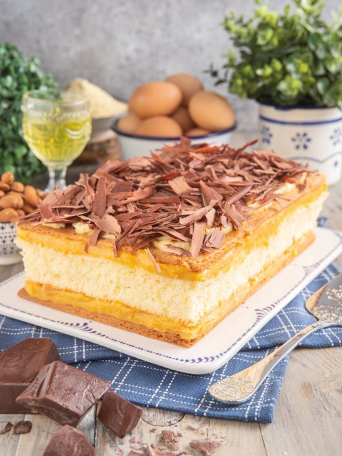 Torta pazientina a strati di pan di spagna e crema pasticcera coperta di scaglie di cioccolato