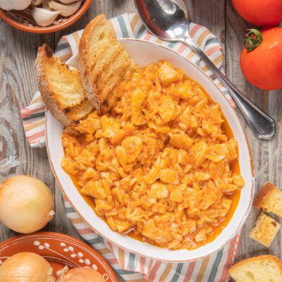 Baccalà in umido alla veneta con salsa di pomodoro, servito con fette di pane tostato