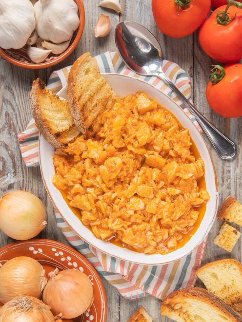 Baccalà in umido alla veneta con salsa di pomodoro, servito con fette di pane tostato