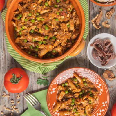 Buridda di seppie con piselli, pinoli e salsa di pomodoro servita in tegame e nel piatto