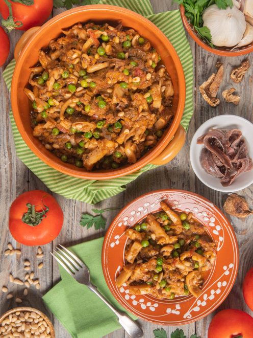 Buridda di seppie con piselli, pinoli e salsa di pomodoro servita in tegame e nel piatto