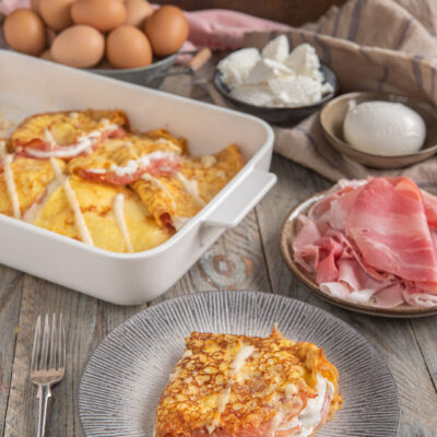Crespelle con prosciutto e besciamella gratinate al forno, servite a fette con farcitura cremosa