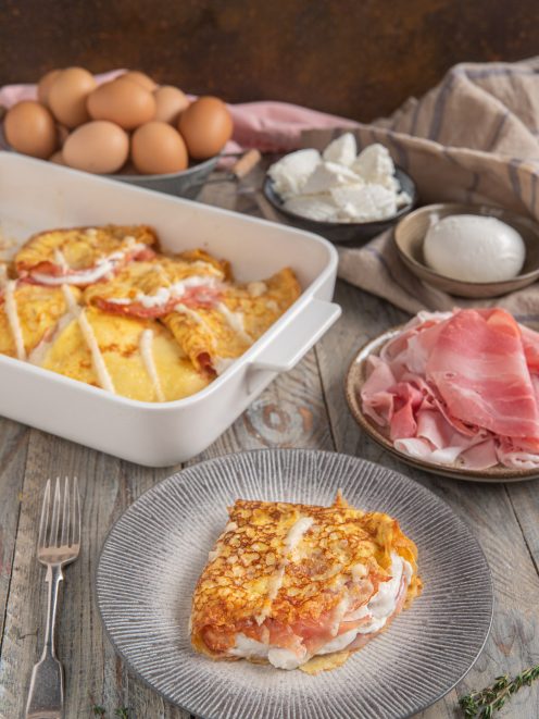 Crespelle con prosciutto e besciamella gratinate al forno, servite a fette con farcitura cremosa