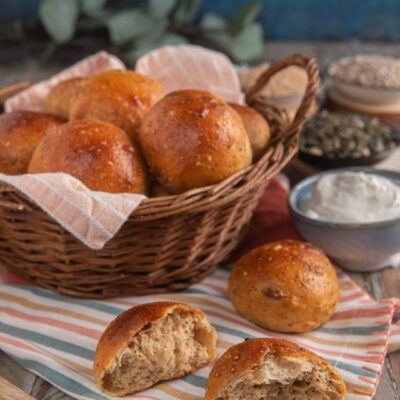 Panini allo yogurt e semi dorati nel cestino, con uno tagliato a meta che mostra la mollica soffice