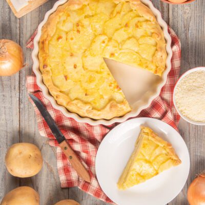 Torta baciocca con fette di patate a vista, una fetta servita accanto alla teglia