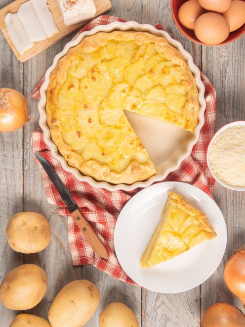 Torta baciocca con fette di patate a vista, una fetta servita accanto alla teglia