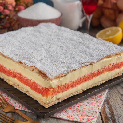 Torta diplomatica a strati con crema pasticcera, pan di Spagna rosso e zucchero a velo