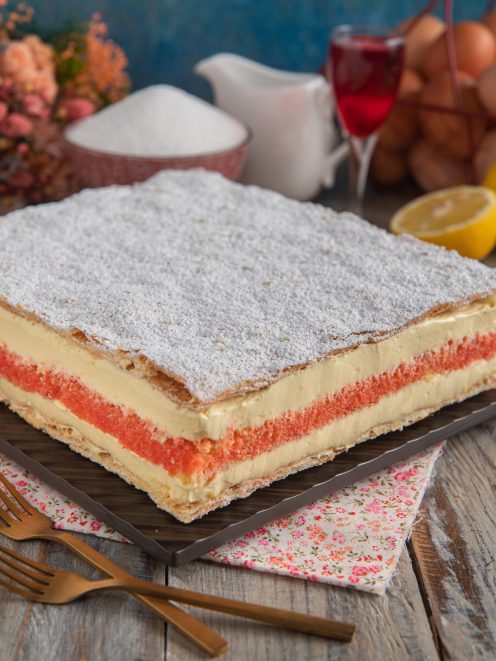 Torta diplomatica a strati con crema pasticcera, pan di Spagna rosso e zucchero a velo