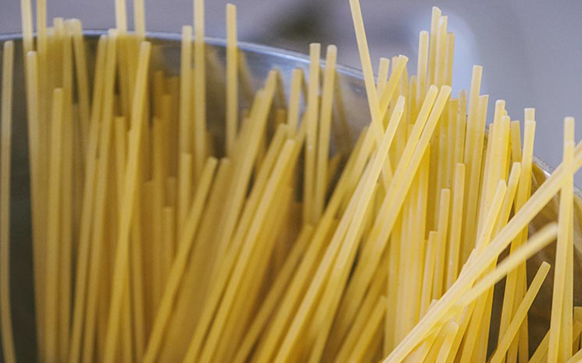 Spaghetti crudi appoggiati alla pentola prima della cottura