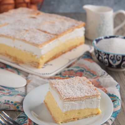 Fetta di bled cake con strati di crema pasticcera e panna tra sfoglie croccanti spolverate di zucchero