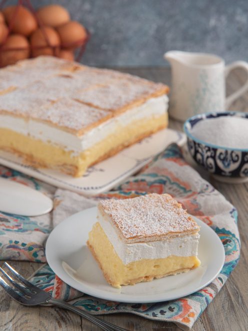 Fetta di bled cake con strati di crema pasticcera e panna tra sfoglie croccanti spolverate di zucchero