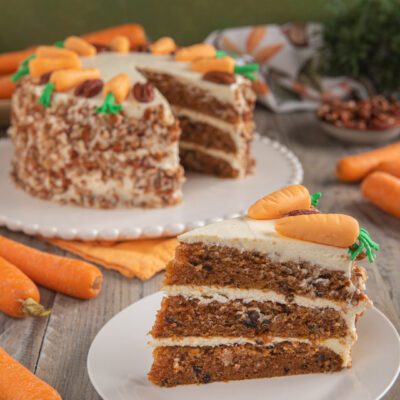 Carrot cake a tre strati con frosting al formaggio, noci tritate e decorazioni a forma di carota