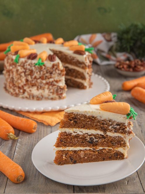 Carrot cake a tre strati con frosting al formaggio, noci tritate e decorazioni a forma di carota