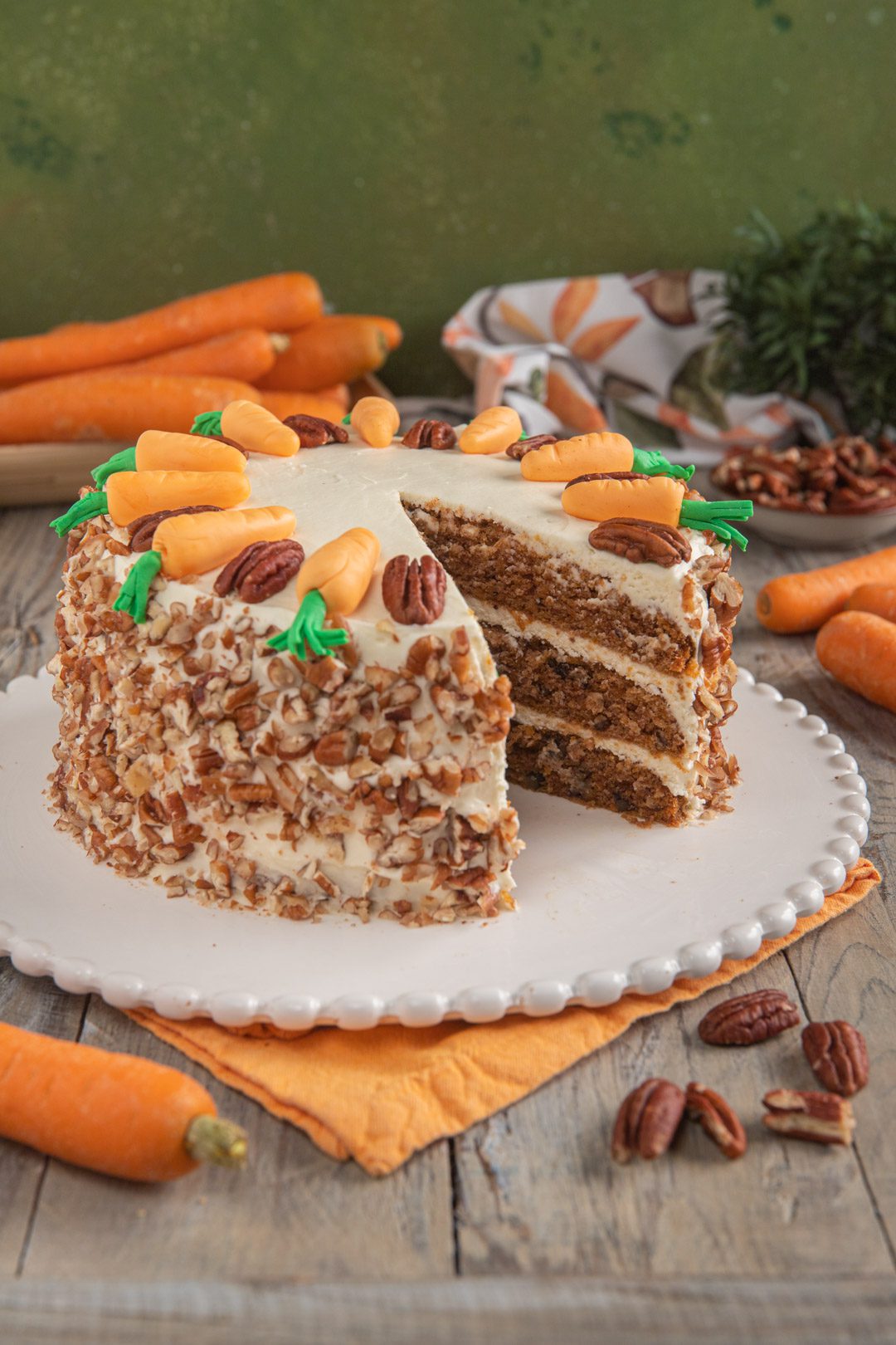 Carrot cake a strati con frosting al cream cheese, granella di noci pecan e decorazioni a forma di carota