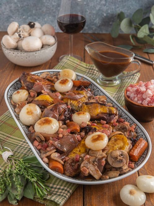 Coq au vin con funghi champignon, cipolline dorate, pancetta e carote in salsa al vino rosso