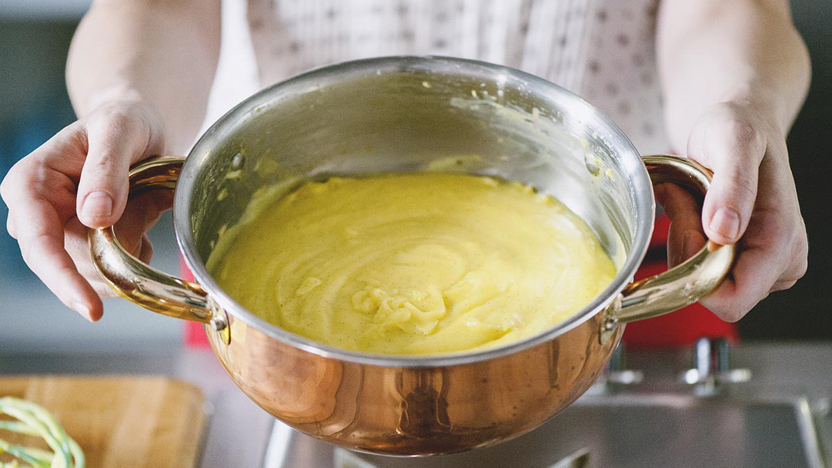 Crema pasticcera liscia e vellutata appena tolta dal fuoco, tenuta tra le mani