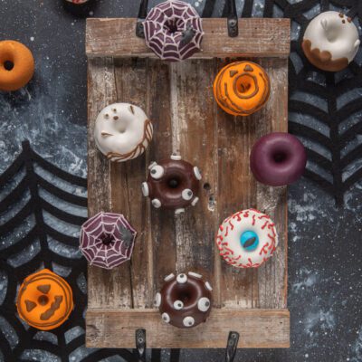 Donuts spaventosi decorati con occhi di zucchero, glassa a ragnatela, zucca e fantasma per Halloween