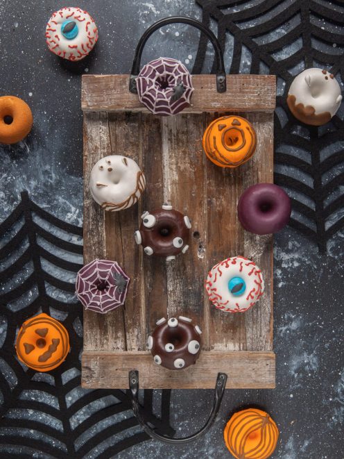 Donuts spaventosi decorati con occhi di zucchero, glassa a ragnatela, zucca e fantasma per Halloween